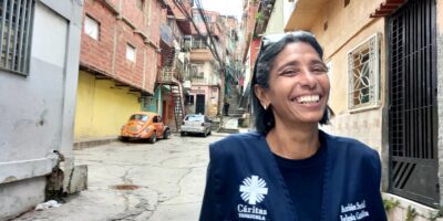 Smiling woman wearing a blue Caritas jacket standing in street setting